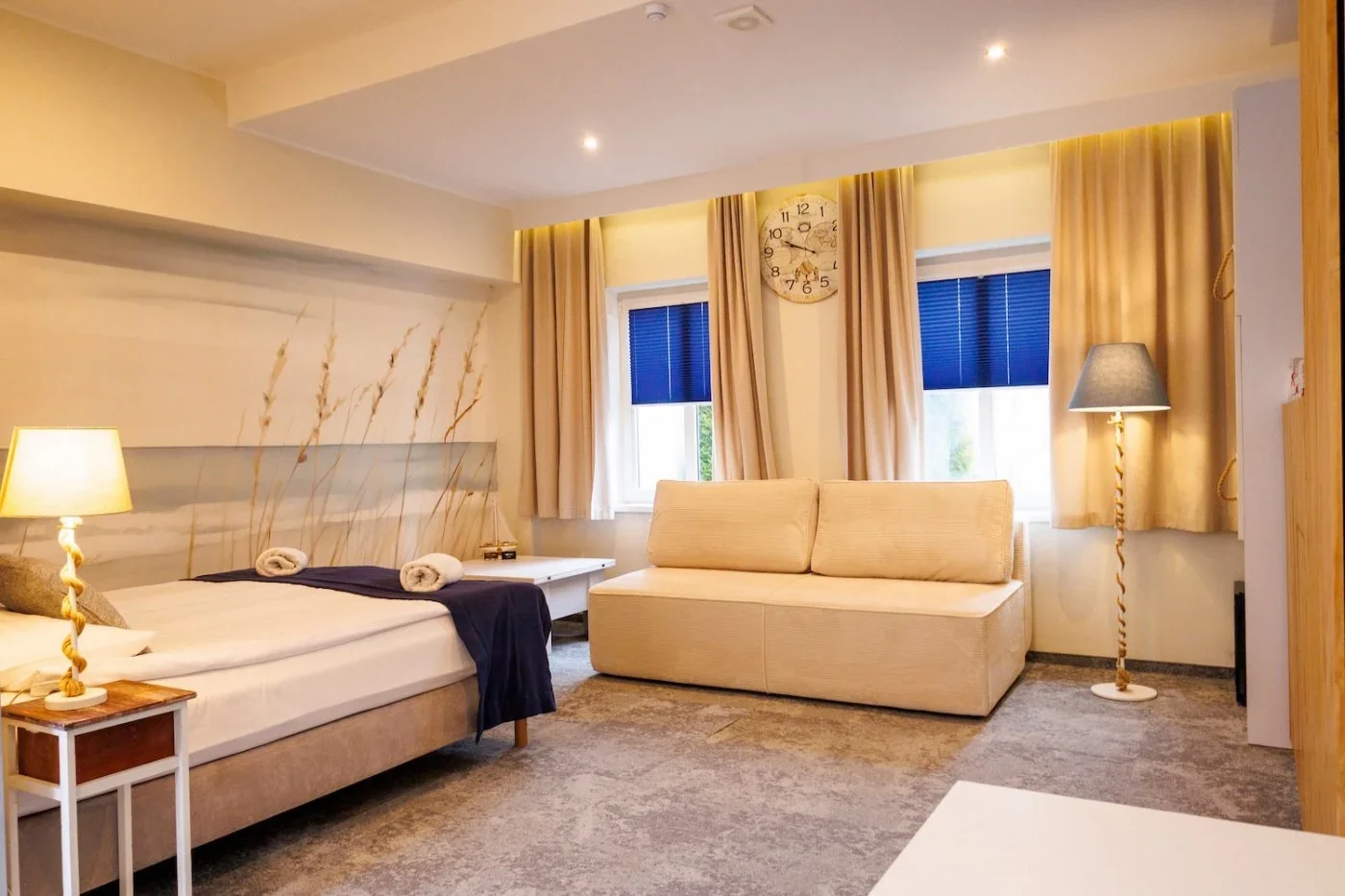 SeaSide Superior room with a double bed, beige sofa and coastal wallpaper.